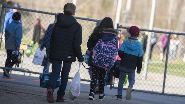 Des enfants gardent une bonne distance entre eux avant d'entrer dans une école.