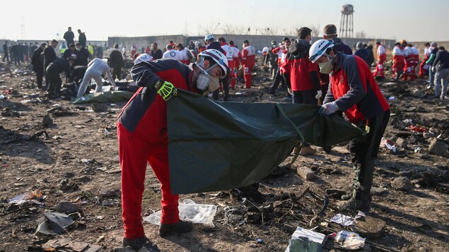 Des secouristes placent les corps des victimes dans des sacs de plastique.