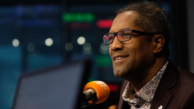 Un homme avec des lunettes dans un studio de radio.