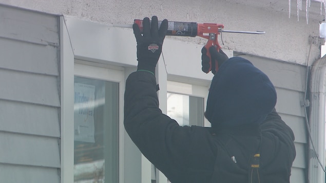 Un homme dépose un produit calfeutrant le long du cadre extérieur d'une fenêtre. Un homme dépose un produit calfeutrant le long du cadre extérieur d'une fenêtre.