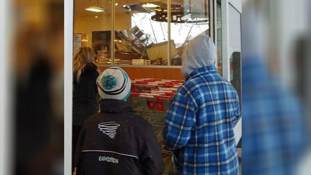 Des clients d'une épicerie de Lévis regarde le toit partiellement effondré de l'immeuble