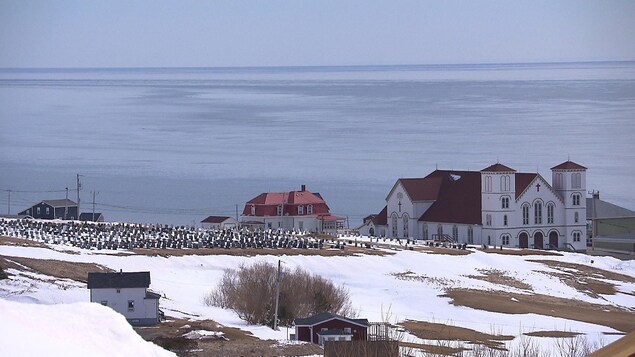 Le cimetière, l'église de Bassin et golfe du Saint-Laurent en hiver.
