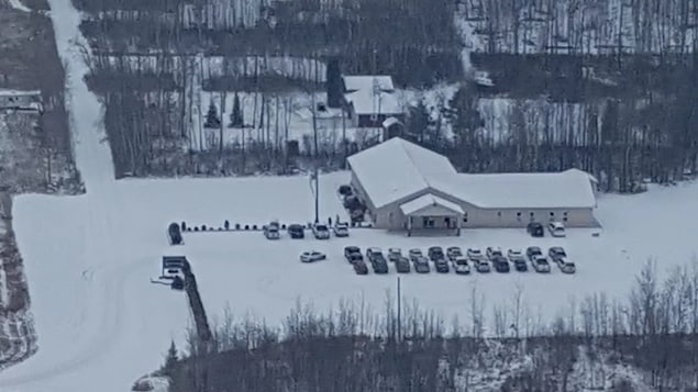L'église, vue de haut, avec un stationnement rempli d'une vingtaine de voitures.