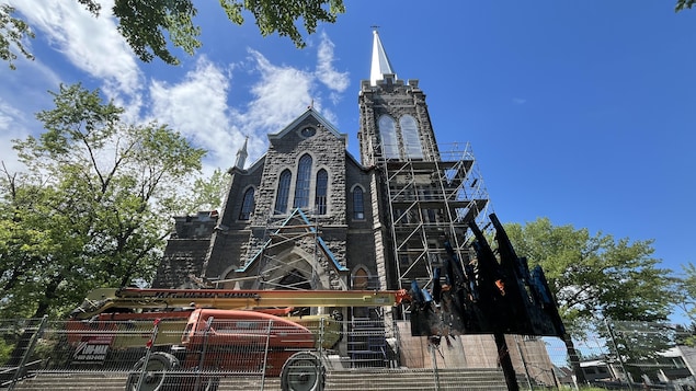 Vue en contre-plongée d'une façade d'église. Des échafauds et un véhicule élévateur sont visibles devant.