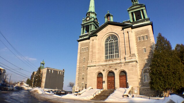 Une église grise avec deux clochers verts et trois portes rouges, par une journée ensoleillée d'hiver. Une église grise avec deux clochers verts et trois portes rouges, par une journée ensoleillée d'hiver.