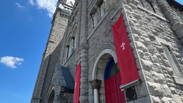 Des bannières rouges avec le logo de The United People of Canada sont accrochées à la façade de l'église Ste-Brigid.