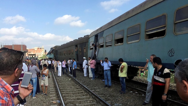 Des Égyptiens constatent l'état de la situation après la collision ferroviaire. Des Égyptiens constatent l'état de la situation après la collision ferroviaire.