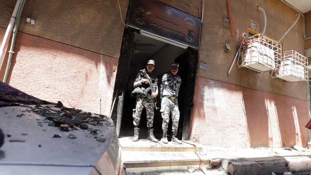 Deux militaires égyptiens surveillent l'entrée d'une église après un incendie.