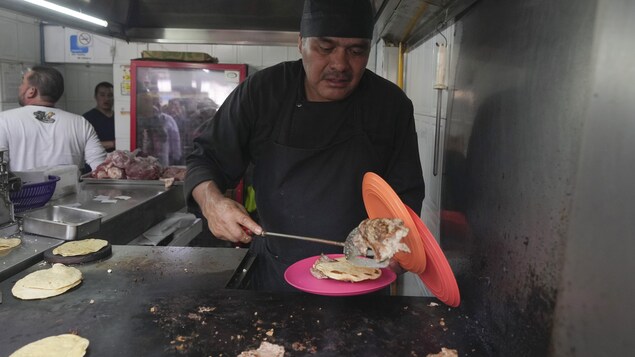 Un cuisinier sert des tacos.