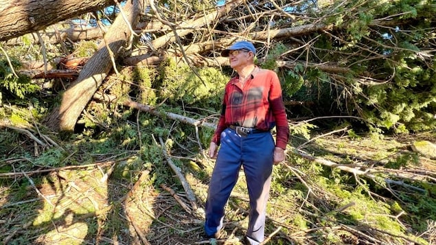 Elbert Murray devant un amas d'arbres cassés.