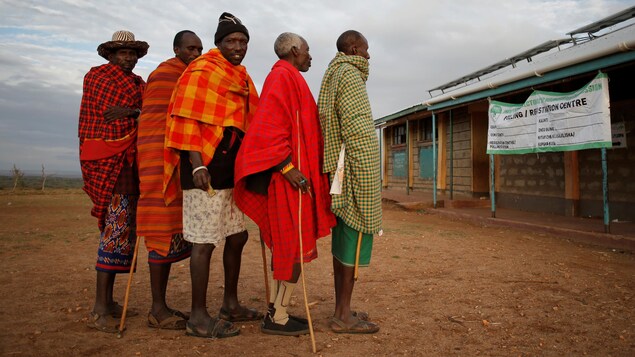 Des hommes aux vêtements colorés font la file.