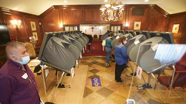 Des électeurs qui portent un masque déposent leur bulletin de vote au Cypress Fairbanks Funeral Home, à Houston.
