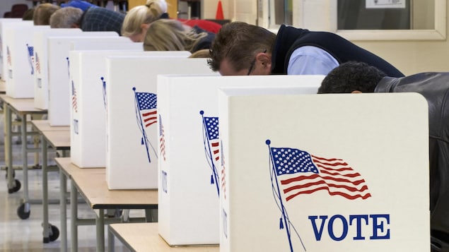 Les électeurs votent le jour du scrutin en déposant leurs bulletins dans des urnes.