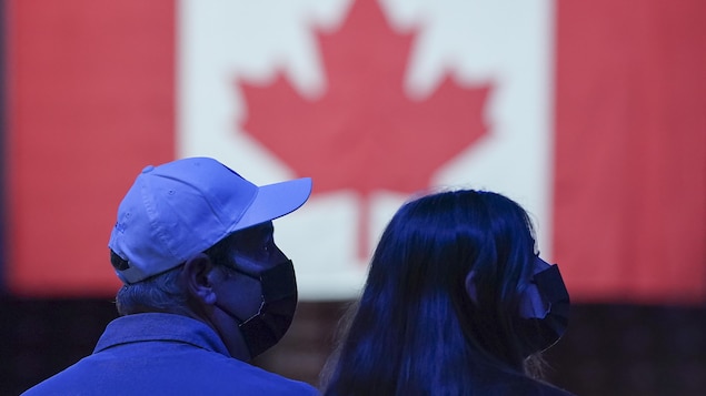 Des électeurs devant un drapeau du Canada.