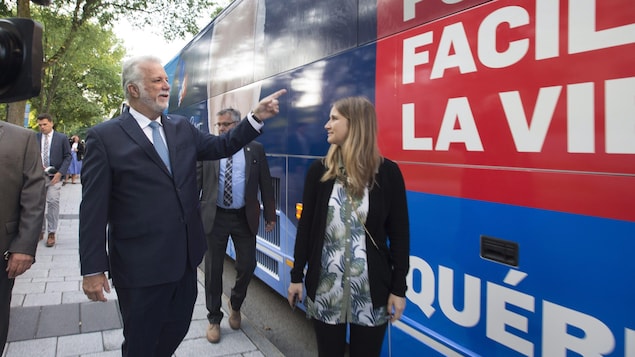 Le chef libéral Philippe Couillard marche à proximité de son autobus de campagne.