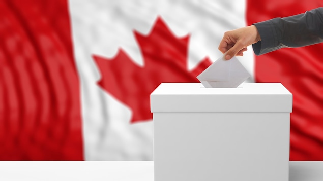 Une main dépose un bulletin de vote dans une boîte de scrutin.