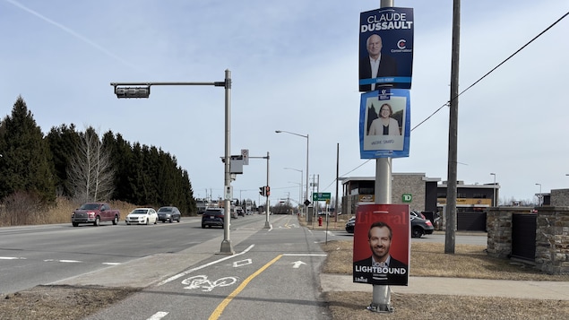 Trois affiches sur un poteau.
