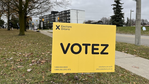 Un panneau d'Élections Ontario devant un bureau de vote, qui dit : Votez.