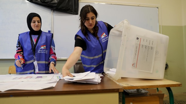 Des travailleuses d'élections ouvrent une boîte de scrutin.