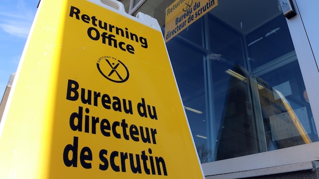 Une affiche jaune posée sur le trottoir indique qu'il s'agit du bureau du directeur de scrutin.