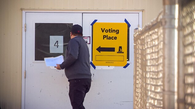 Un homme qui s'en va voter est en train d'ouvrir la porte.