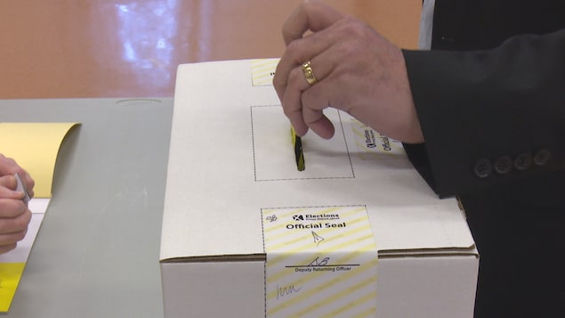 Un homme dépose un bulletin de vote dans une boîte de scrutin
