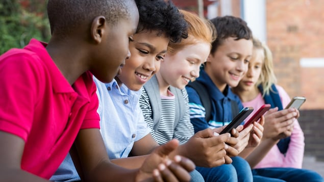 Des enfants utilisant un téléphone intelligent.