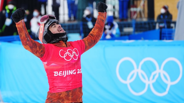 Éliot Grondin célèbre sa médaille d'argent en snowboard cross aux Jeux de Pékin.