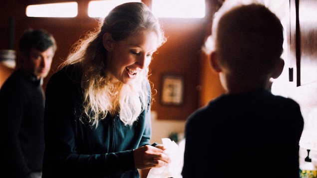 Une femme blonde penchée en avant sourit. 
