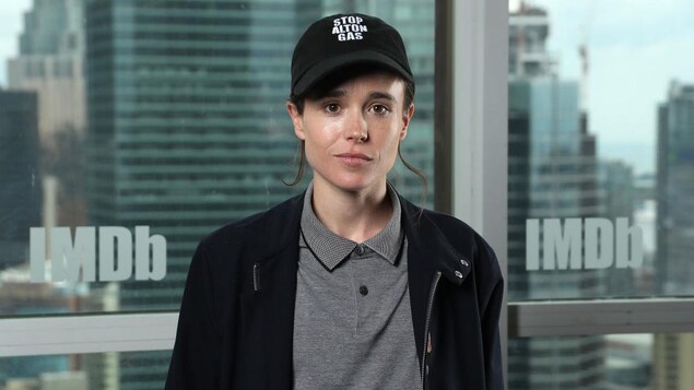 Elliot Page porte une casquette noire et un chandail gris.