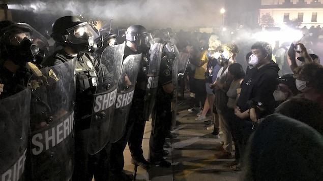 Des membres de l'antiémeute font face à des manifestants dans la nuit.