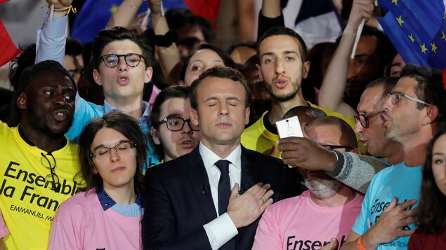 Emmanuel Macron entouré de partisans portant des chandails avec son slogan de campagne "Ensemble la France".