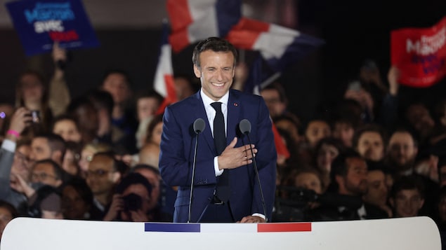 Emmanuel Macron a la main sur le coeur, souriant devant ses partisans. 