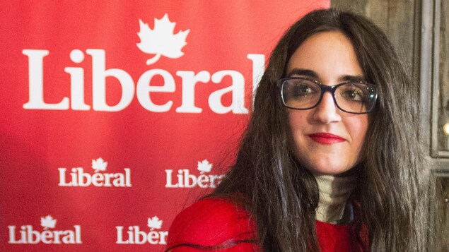Emmanuella Lambropoulos, en rouge, devant une affiche du Parti libéral.