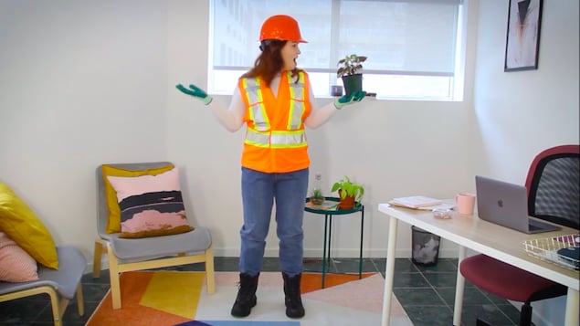 Une fille habillée en employée municipale tient une plante dans ses mains.
