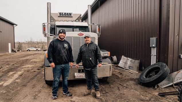 Père et fils qui posent devant un camion sur le site de la ferme familiale.