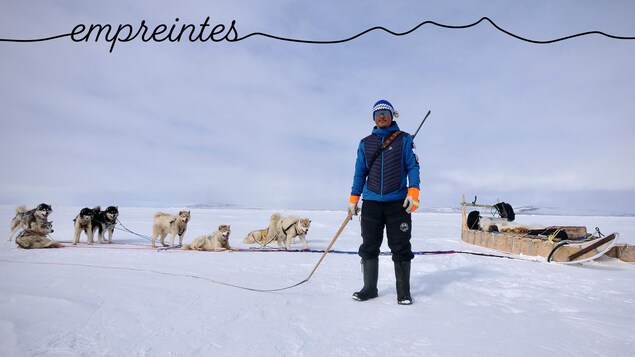 Devon Manik est debout sur la banquise, un fouet à la main devant son traîneau avec ses chiens, au mois de juin près de Resolute Bay, dans le nord du Nunavut.