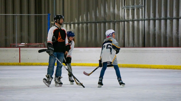 Adam Lemay et deux élèves sont sur la patinoire.