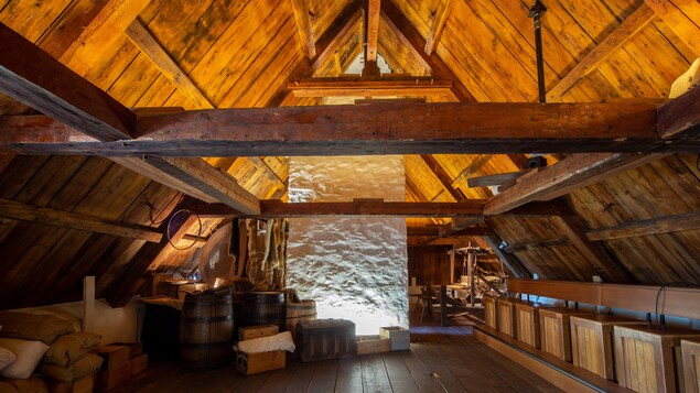 Un grenier avec des poutres de bois, des caissons et des sacs de sable dans un manoir du 18e siècle.