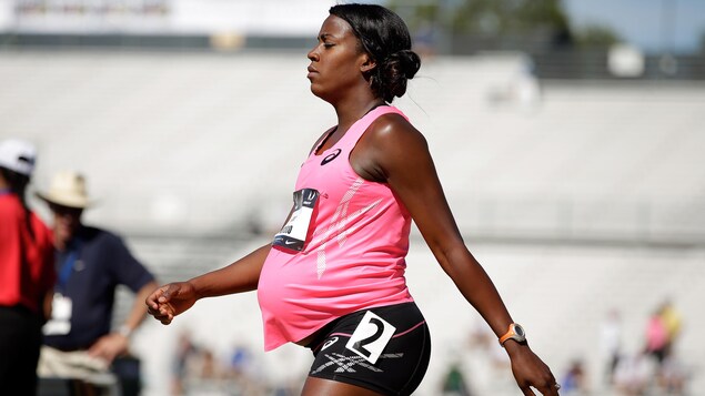 L'athlète enceinte marche sur une piste d'athlétisme.