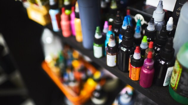 On voit en gros plan des bouteilles de plastique de différentes couleurs posées sur des étagères. On voit en gros plan des bouteilles de plastique de différentes couleurs posées sur des étagères.