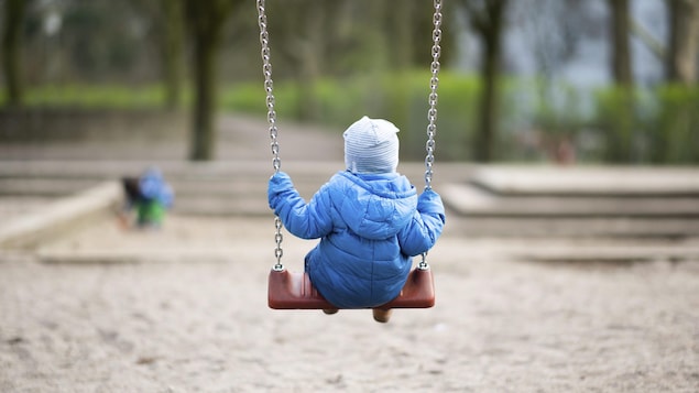 Un jeune enfant se balance dans un parc.