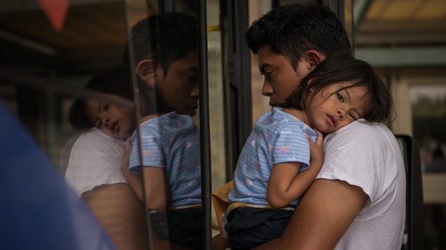 Un homme tient dans ses bras une petite fille.