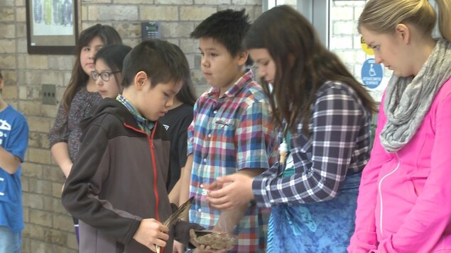Enfant tient une plume et du tabac qui fume et passe devant d'autres enfants. Enfant tient une plume et du tabac qui fume et passe devant d'autres enfants.