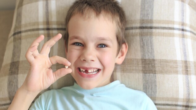 Un garçon se réjouit d'avoir perdu l'une de ses dents de bébé.