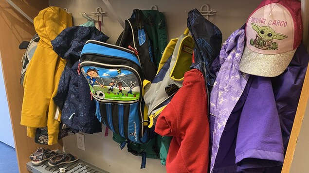 Des manteaux d'enfants sur des crochets dans le vestiaire d'une garderie.