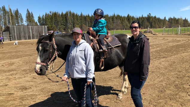 Une fillette à cheval accompagnée de maman et d'une instructrice