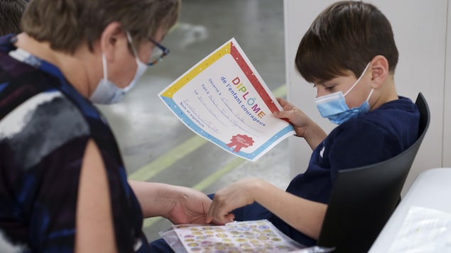 Un garçon choisit un certificat après avoir reçu une dose du vaccin contre la COVID-19. 