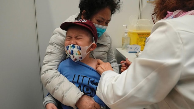 Un petit garçon pleure dans les bras de sa mère en recevant un vaccin.
