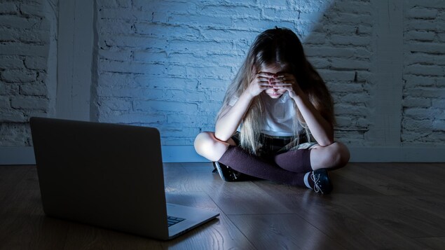 Fille effrayée, victime de cyberintimidation et de harcèlement en ligne avec son ordinateur portable.
